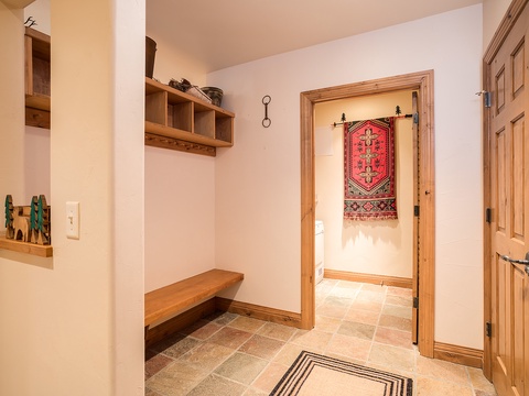Step into your welcoming entryway with warm wood accents, a cozy bench for settling in, and thoughtful storage. A handwoven tapestry adds artisan charm to the space.