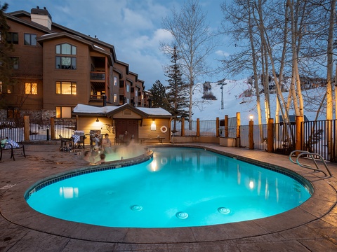 Outdoor pool and hot tub area at twilight, offering mountain slope views and perfect après-ski relaxation after a day on the slopes nearby.