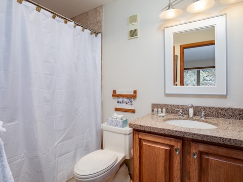 Freshen up in your private bathroom featuring granite countertops, warm wood cabinetry, and a relaxing shower-tub combo—your peaceful retreat after a day of adventure.