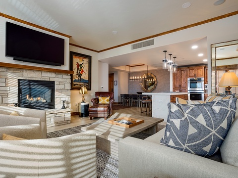 Sink into plush seating by the stone fireplace, where warm wood tones and mountain-inspired décor create your perfect après retreat with open views to the full kitchen.