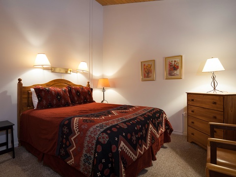 Step into this welcoming bedroom where warm lighting and southwestern-inspired bedding invite you to unwind after your mountain adventures.
