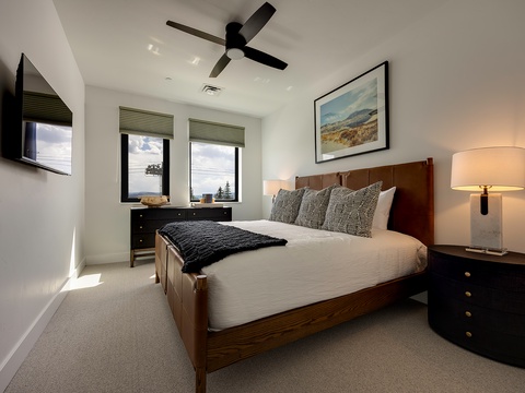 Drift off in your restful bedroom, where a plush bed, soft lighting, and a gentle ceiling fan create a peaceful retreat after exploring the surrounding scenery.