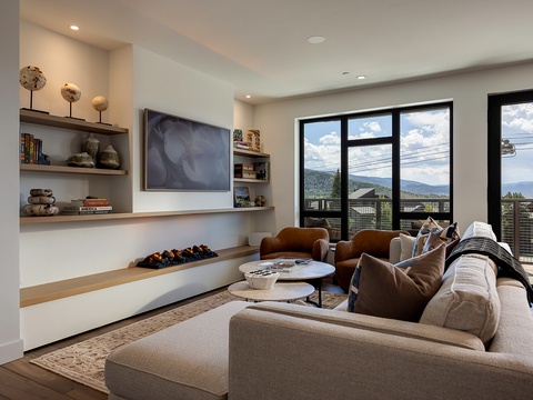 Relax into plush seating with sweeping mountain views through oversized windows. The modern fireplace and warm wood accents create an inviting space where you'll love unwinding after your day.