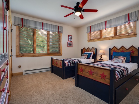Rest easy in this charming bedroom featuring two handcrafted star-adorned beds, perfect for families or friends. The ceiling fan keeps you cool while playful red and blue accents create a cozy mountain retreat atmosphere.