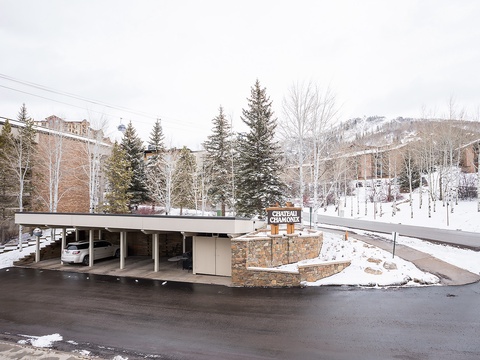 The property sits nestled in a scenic mountain setting with covered parking and easy access to winter recreation, surrounded by snow-dusted trees and rolling alpine terrain.