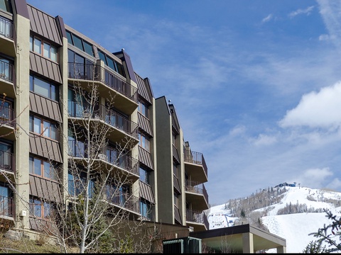 Multi-story vacation rental building set against snow-covered mountain slopes, offering ski-in/ski-out access and stunning alpine scenery in a prime winter resort location.
