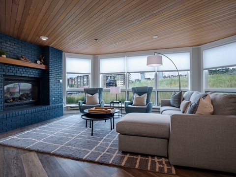 Settle into plush seating by your fireplace, where warm wood tones and floor-to-ceiling windows frame serene views. Natural light floods your space, perfect for morning coffee or evening relaxation.