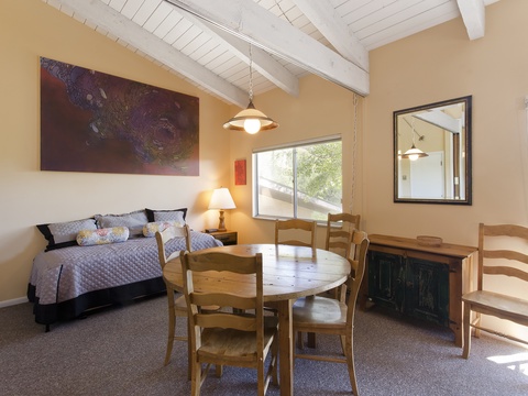 Open-plan comfort with rustic charm—your cozy bed awaits under beamed ceilings, while your dining area sits bathed in natural light for easy mornings and leisurely meals together.