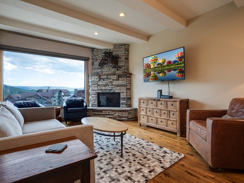 Unwind in your inviting living room with comfortable seating, a cozy fireplace, and stunning mountain views framed by large windows—your perfect retreat after a day of adventure.