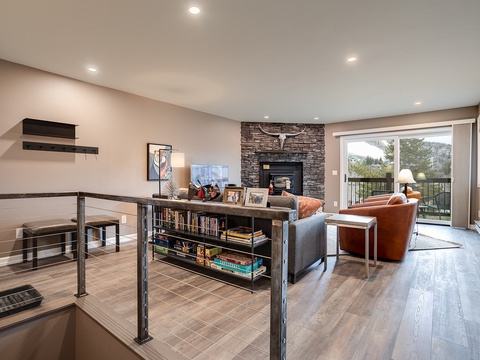 Curl up in your cozy living space with a stone fireplace, stylish seating, and a private balcony overlooking peaceful greenery—your perfect mountain retreat awaits.