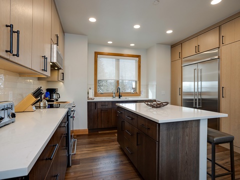 Picture yourself preparing your favorite meals in this bright, modern kitchen with rich wood tones, quartz countertops, stainless appliances, and a center island perfect for morning coffee or casual dining.