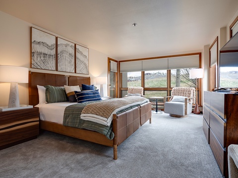 Sink into plush bedding and wake to stunning mountain views through expansive windows. Your peaceful retreat features warm wood tones, elegant artwork, and a cozy seating nook perfect for morning coffee.