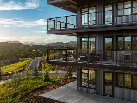 Modern multi-level property nestled in a serene mountain setting with sweeping views and spacious balconies bathed in golden evening light.