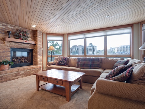 Sink into plush seating by your warming fireplace while panoramic windows frame the cityscape—your cozy retreat awaits with comfort and style.