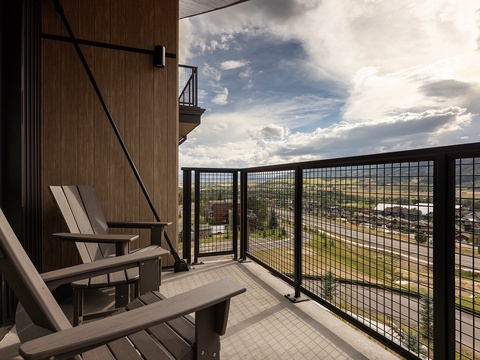 Settle into your private balcony with a view that stretches across town to dramatic mountain peaks. Watch clouds drift by as you relax in modern outdoor seating—perfect for morning coffee or evening unwinding.