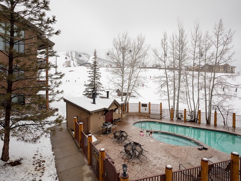Heated outdoor pool nestled slopeside offers year-round access, with ski slopes and mountain gondola in full view. Winter charm meets alpine convenience in this mountain resort setting.
