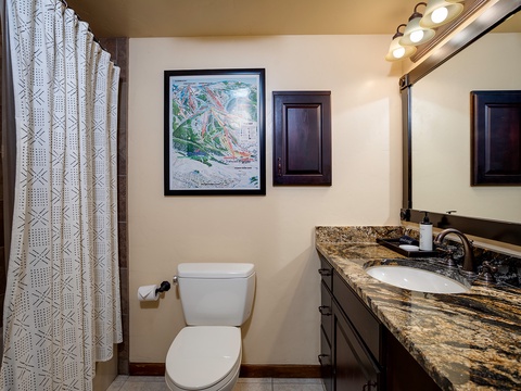 Your private bathroom features a granite-top vanity, modern fixtures, and bright lighting—perfect for refreshing after a day on the slopes shown on the trail map above.