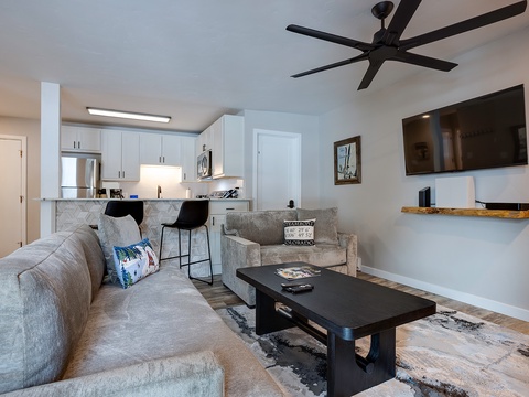Sink into plush seating and enjoy movie nights under the gentle breeze of a modern fan. The open layout flows seamlessly to a bright, fully-equipped kitchen—perfect for your home-away-from-home stay.