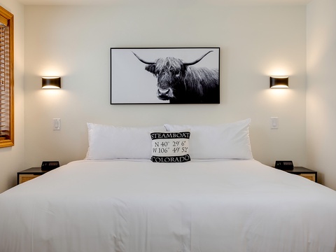 Sink into crisp white linens beneath modern wall sconces that cast a warm glow. Thoughtful design meets mountain charm with touches of local character.