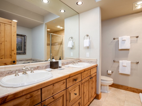 Refresh after your day's adventures in this spacious bathroom with double vanities, warm wood accents, and plush white towels waiting for you.