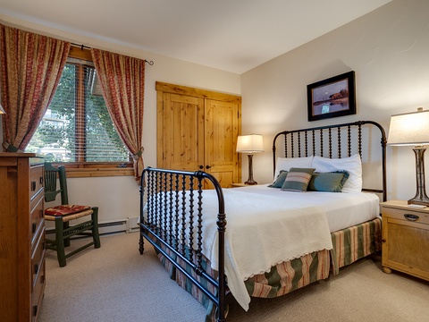 Unwind in this cozy bedroom featuring a charming iron bed, rustic pine furniture, and warm textiles that invite restful nights after your mountain adventures.