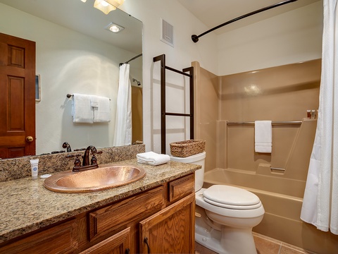 Step into your private bathroom featuring a granite vanity, copper sink, and tub-shower combo with fresh towels ready for your stay.