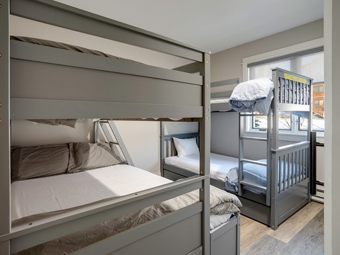 A cozy bunk room with clean linens and soft natural light invites families to settle in together after a day of mountain adventures.