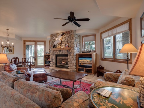 Sink into plush seating by the stone fireplace, where warm lighting and mountain-home charm create your perfect retreat after a day of adventure.