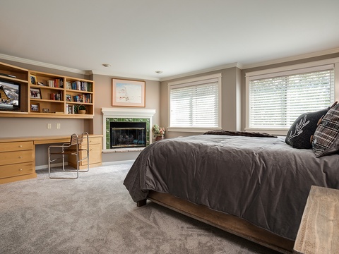 Picture yourself unwinding in this spacious bedroom with plush bedding, a cozy fireplace, and a dedicated workspace—your perfect retreat after mountain adventures.