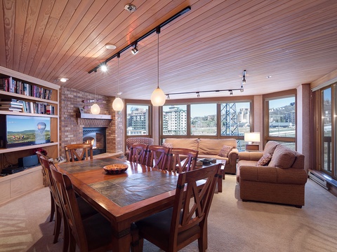 Gather around the handsome dining table while natural light pours through expansive windows. Relax by the cozy fireplace in this inviting space designed for memorable evenings together.