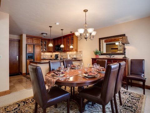 Gather around this elegant dining table, where your group can enjoy home-cooked meals together in comfort. Rich wood cabinetry and warm lighting create the perfect setting for memorable evenings.