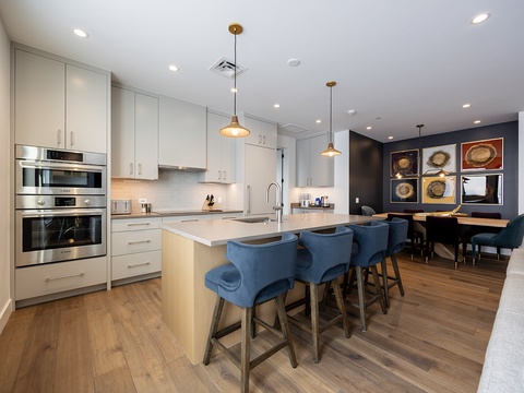 Modern open-concept kitchen and dining space featuring sleek appliances, bright white cabinetry, and stylish pendant lighting. Perfect for gathering at the spacious island or hosting memorable dinners.