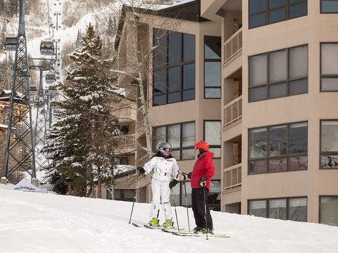 Ski-in, ski-out property situated directly on the slopes with a chairlift nearby. Modern multi-level building with balconies overlooking the snowy mountain terrain.