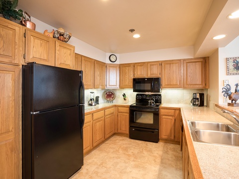 Your fully-equipped kitchen features warm oak cabinetry, modern black appliances, and plenty of counter space for preparing delicious home-cooked meals during your stay.