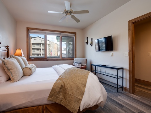 Slip into crisp linens and unwind in your serene bedroom, featuring a plush bed, flat-screen TV, and ceiling fan for ultimate comfort after a day of adventure.