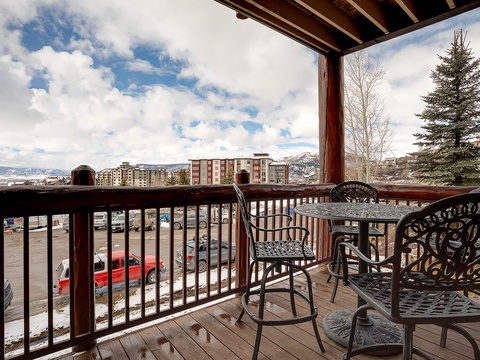 A covered mountain retreat frames winter's beauty, where nearby peaks and evergreens meet an open sky. This outdoor seating provides a serene spot to take in the scenic surroundings during your mountain getaway.