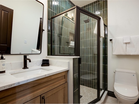 Step into your private spa-like retreat, where calming green tiles and a spacious walk-in shower invite you to refresh and unwind after a day of adventure.