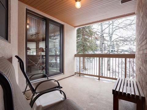 Your private balcony invites you to unwind in your chair while taking in peaceful winter views of snow-dusted trees and serene surroundings—a perfect spot for morning coffee or evening relaxation.