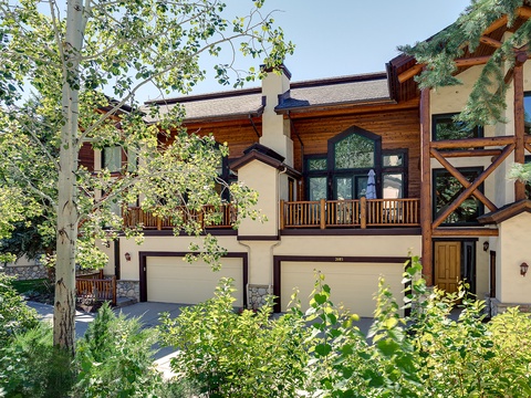 A striking mountain-style property featuring wood and stucco architecture framed by aspens and evergreens. The two-story building offers private garage access and a welcoming entrance nestled in natural surroundings.