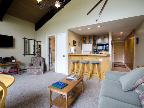 You'll love gathering in this open living space where vaulted ceilings with rustic beams create an airy feel and the fully equipped kitchen bar invites conversation over morning coffee or après-ski snacks.