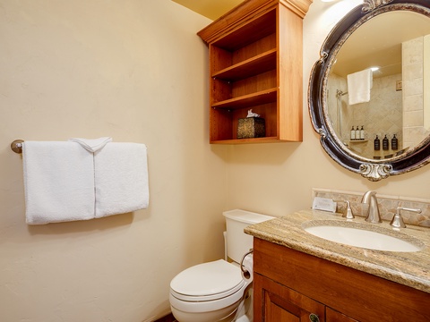 Your private bathroom features a granite vanity, elegant mirror, and crisp linens, blending timeless charm with modern comforts for your stay.