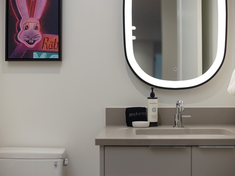 Freshen up in your sleek, modern bathroom featuring a backlit vanity mirror, premium amenities, and contemporary finishes—everything you need to start your day refreshed.