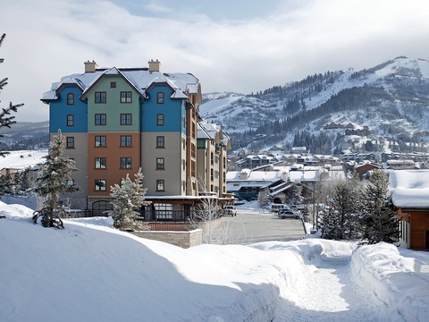 Colorful alpine property nestled in a snow-covered village, with ski slopes rising in the background—a perfect mountain retreat setting.