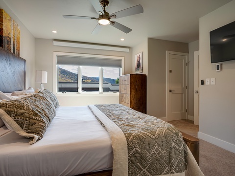 Drift off in this serene bedroom with crisp linens, a cozy ceiling fan, and peaceful lake and mountain views framing your morning light.