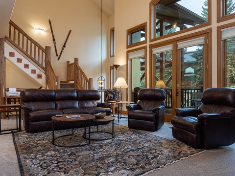 Sink into plush leather seating in your spacious living room, where floor-to-ceiling windows frame lush forest views and a warm, inviting atmosphere welcomes you home.