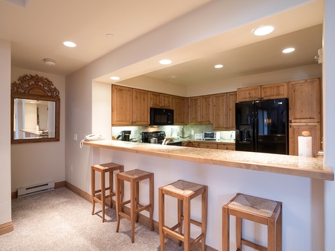 Your fully equipped kitchen features warm wood cabinetry, modern appliances, and a breakfast bar perfect for morning coffee or casual meals with loved ones.
