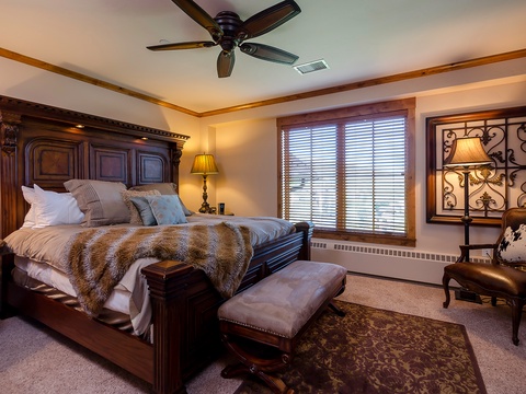 Sink into this luxurious bed with plush linens and a cozy fur throw, where your restful nights are cooled by a ceiling fan and warmed by elegant décor.