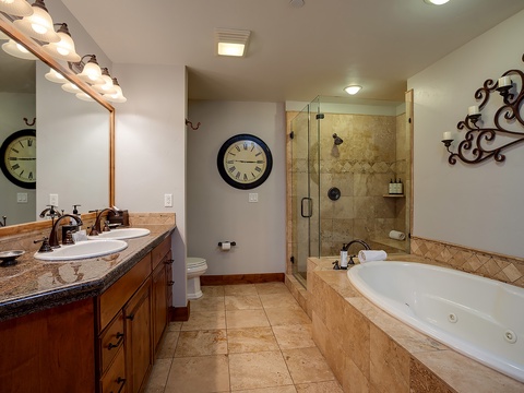 Unwind in your spacious bathroom featuring dual vanities, a luxurious jetted tub, and a walk-in shower. Warm lighting and elegant finishes create your perfect retreat.