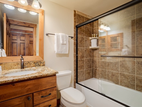 Your private bathroom features a granite vanity, fresh towels, and a tub-shower combo with glass doors—perfect for unwinding after a day of adventure.