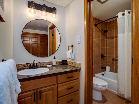 Your private bathroom blends rustic charm with modern comfort, featuring warm wood accents, a spa-like shower-tub combo, and soft lighting to help you unwind after each adventure-filled day.
